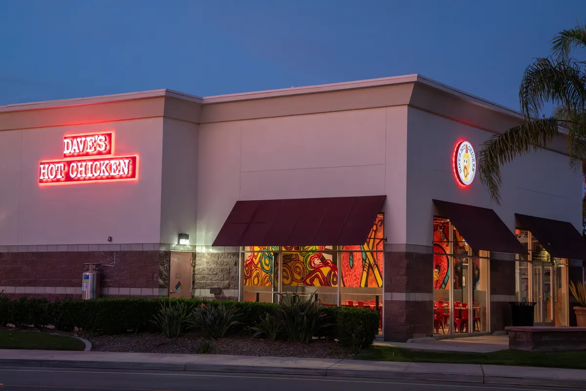 Dave’s Hot Chicken storefront at dusk with its neon sign